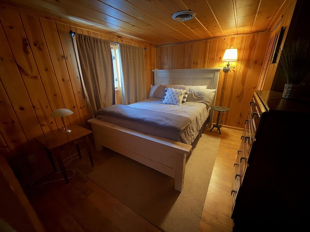 bedroom with light wood-type flooring, wooden ceiling, and wooden walls