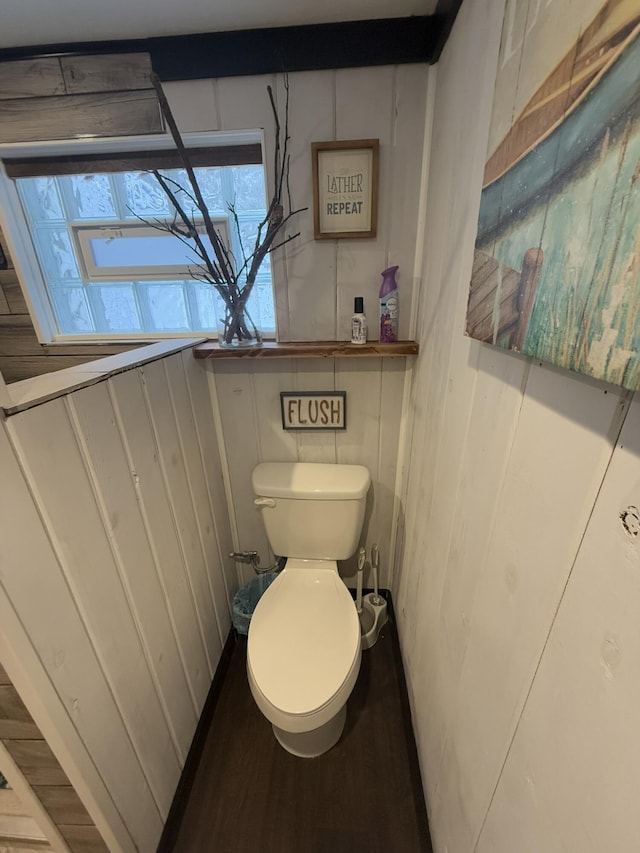 bathroom featuring wooden walls and toilet