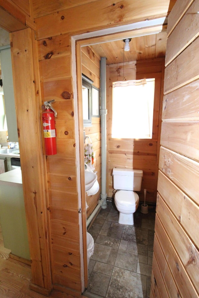 bathroom with wooden ceiling, toilet, and wood walls