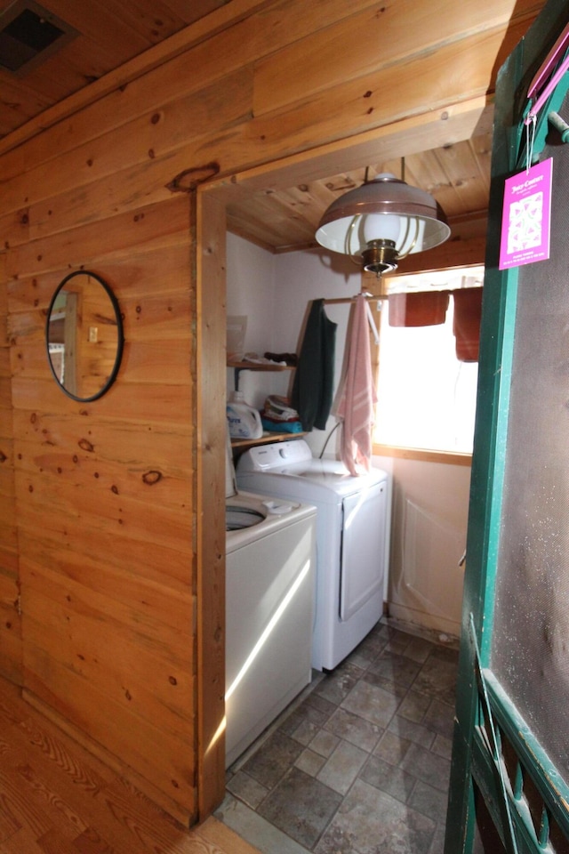 laundry room with separate washer and dryer and wood walls