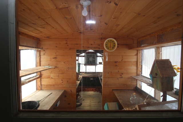 interior space featuring wood ceiling, lofted ceiling, and wooden walls