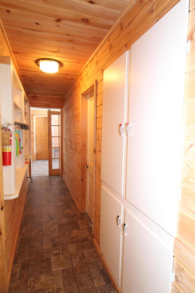 corridor with wood ceiling, wooden walls, and french doors