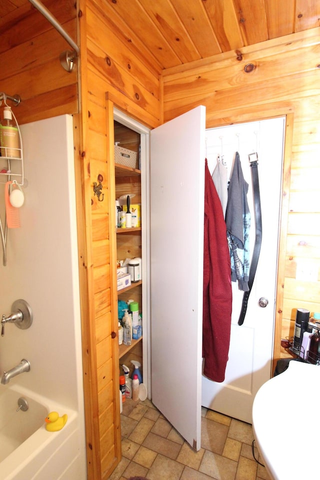 bathroom featuring bathtub / shower combination, wooden ceiling, and wood walls