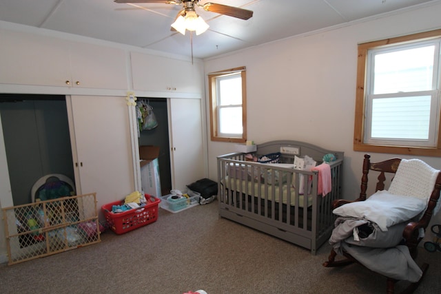 bedroom featuring a nursery area, ceiling fan, and carpet flooring