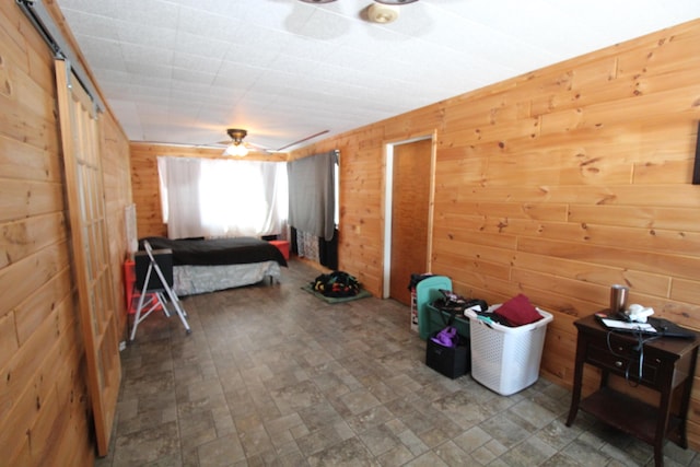 bedroom featuring ceiling fan and wooden walls