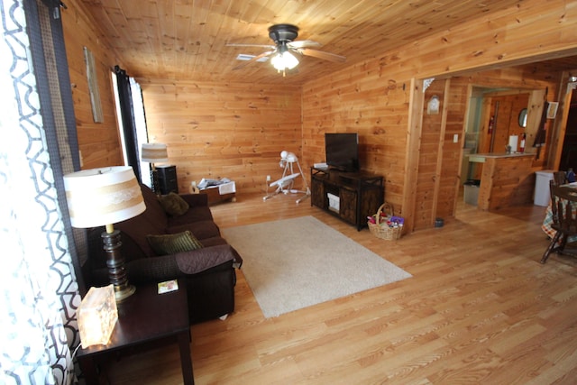 living room featuring ceiling fan, wooden ceiling, wooden walls, and light hardwood / wood-style flooring