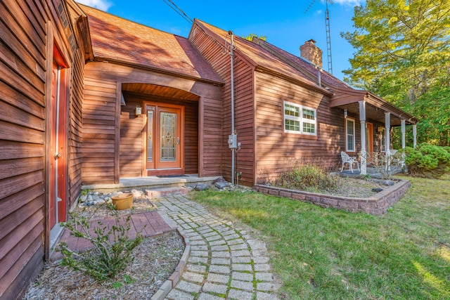 entrance to property featuring covered porch and a lawn