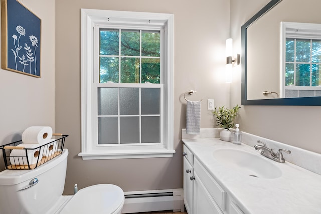 bathroom featuring a healthy amount of sunlight, a baseboard heating unit, vanity, and toilet