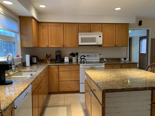 kitchen with sink, light stone counters, light tile patterned floors, a kitchen island, and white appliances