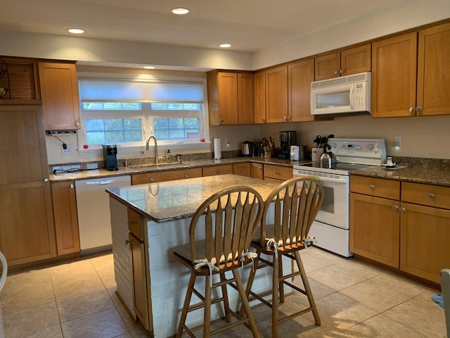 kitchen featuring sink, white appliances, stone counters, a kitchen bar, and light tile patterned flooring