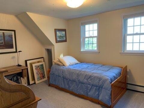 carpeted bedroom featuring multiple windows and a baseboard radiator