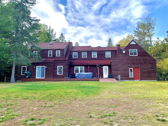 back of property featuring a wooden deck and a yard