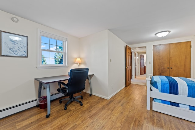 bedroom featuring a baseboard heating unit and light wood-type flooring