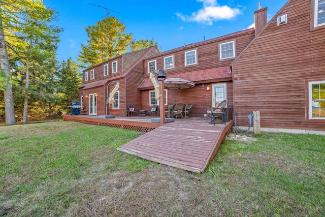 rear view of property with a wooden deck and a lawn