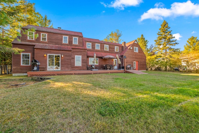 back of property featuring a wooden deck and a lawn