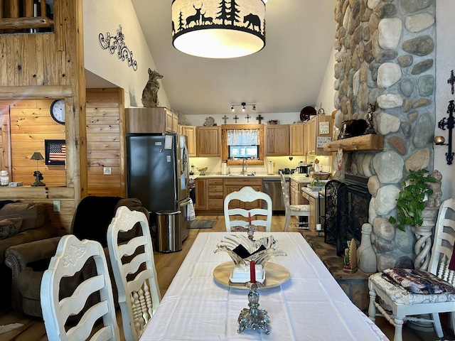 dining space featuring vaulted ceiling, sink, a fireplace, and light hardwood / wood-style flooring