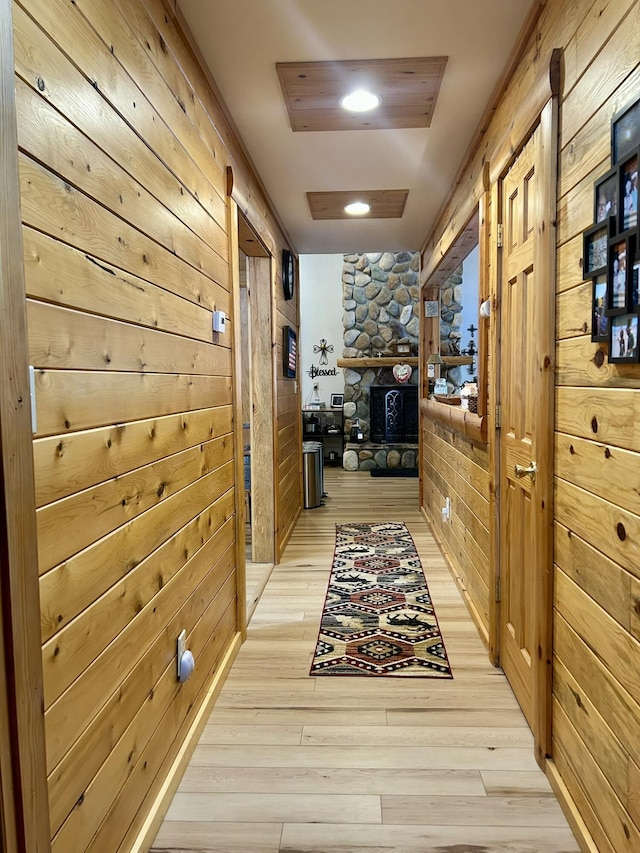 hall featuring wooden walls and light hardwood / wood-style flooring