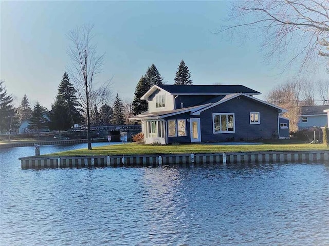 back of house with a lawn and a water view