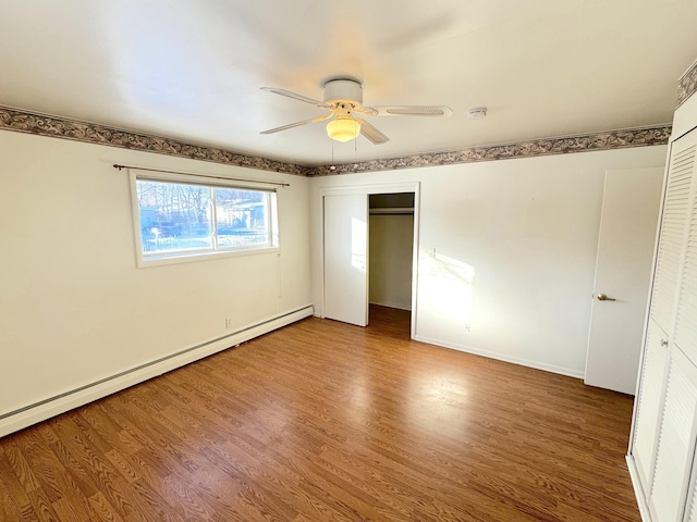 unfurnished bedroom featuring a baseboard heating unit, hardwood / wood-style floors, and ceiling fan