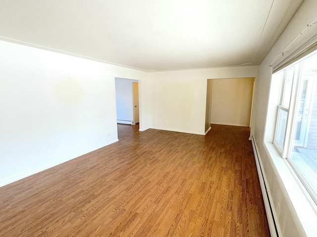 spare room featuring a baseboard heating unit and wood-type flooring