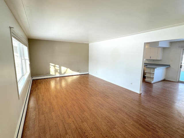 unfurnished living room featuring hardwood / wood-style flooring and a baseboard heating unit