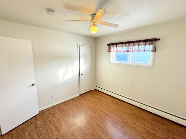 unfurnished room featuring a baseboard heating unit, ceiling fan, and light hardwood / wood-style flooring