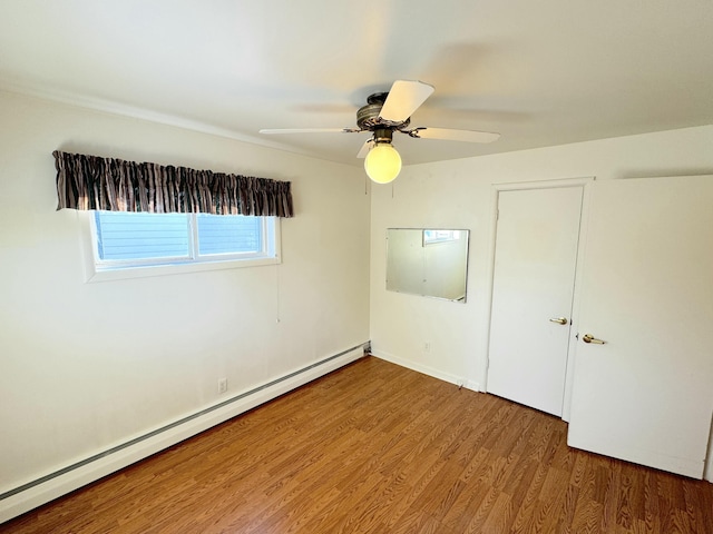 unfurnished bedroom featuring hardwood / wood-style flooring, ceiling fan, and baseboard heating