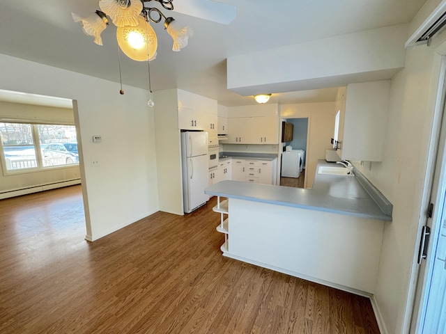 kitchen featuring dark hardwood / wood-style floors, washer / clothes dryer, white cabinets, kitchen peninsula, and white appliances