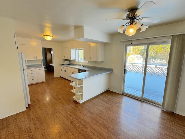 kitchen with sink, white cabinets, light hardwood / wood-style floors, kitchen peninsula, and white appliances