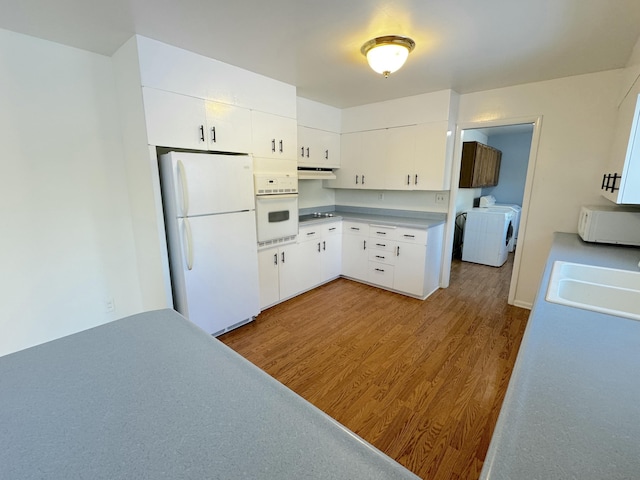 kitchen featuring sink, white appliances, washing machine and dryer, light hardwood / wood-style floors, and white cabinets