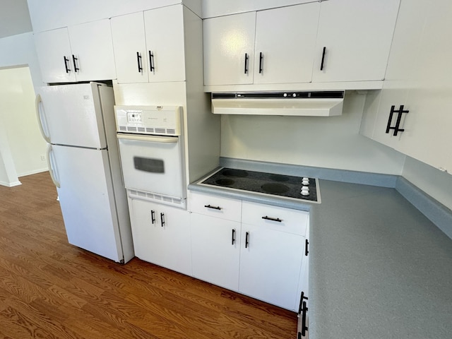 kitchen with dark wood-type flooring, white cabinets, and white appliances