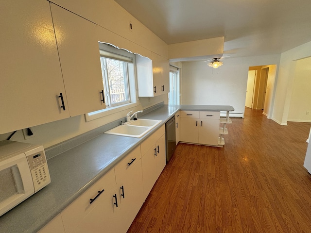 kitchen featuring wood-type flooring, kitchen peninsula, dishwasher, and white cabinets