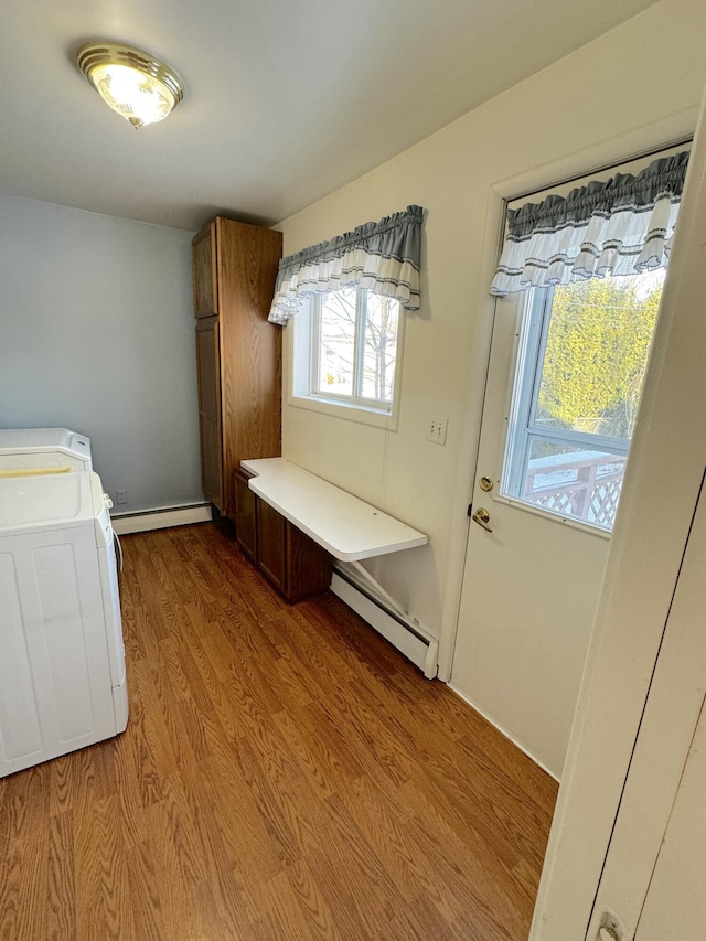 laundry area with a baseboard heating unit, light hardwood / wood-style flooring, and cabinets