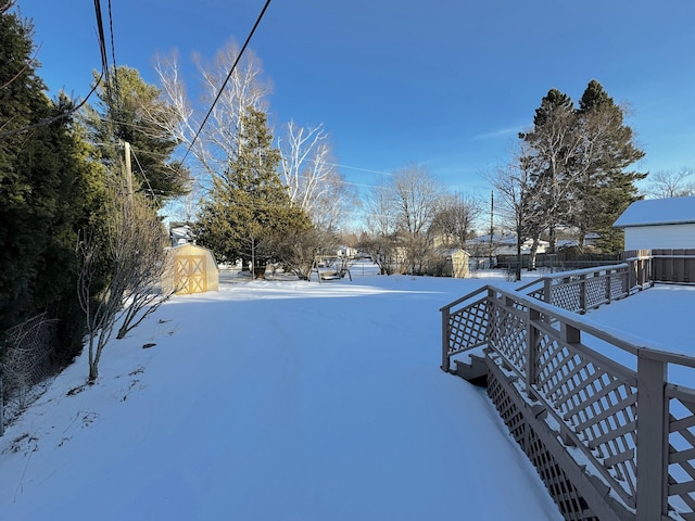 yard layered in snow featuring a storage shed