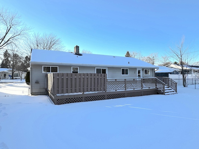 snow covered back of property with a wooden deck