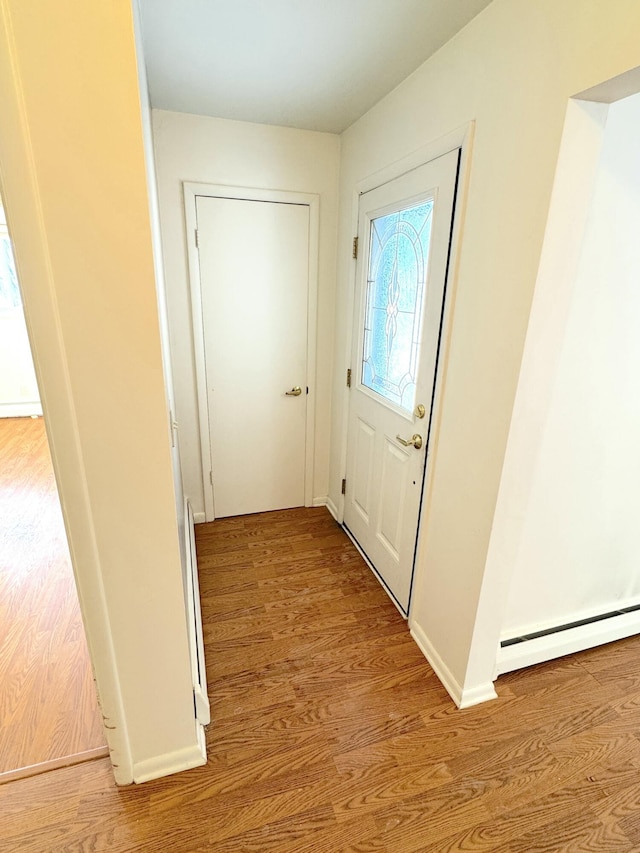 interior space with a baseboard heating unit and light hardwood / wood-style floors