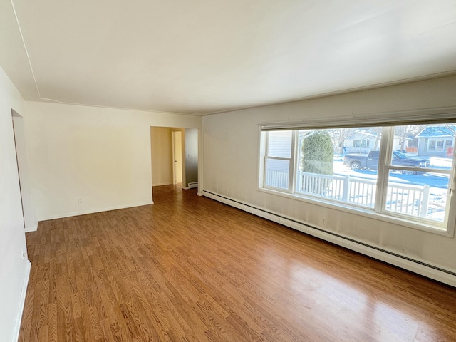 unfurnished room featuring hardwood / wood-style floors and baseboard heating