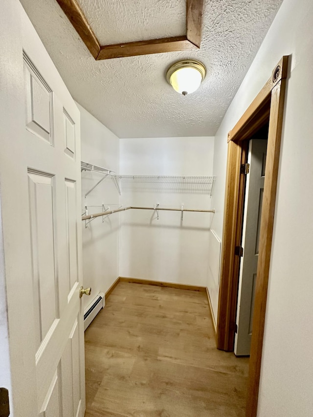 spacious closet with a baseboard radiator and light hardwood / wood-style flooring