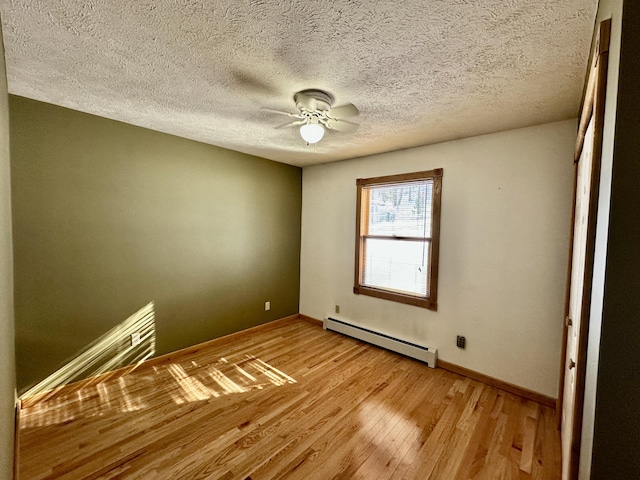 spare room with a baseboard heating unit, a textured ceiling, ceiling fan, and light hardwood / wood-style flooring