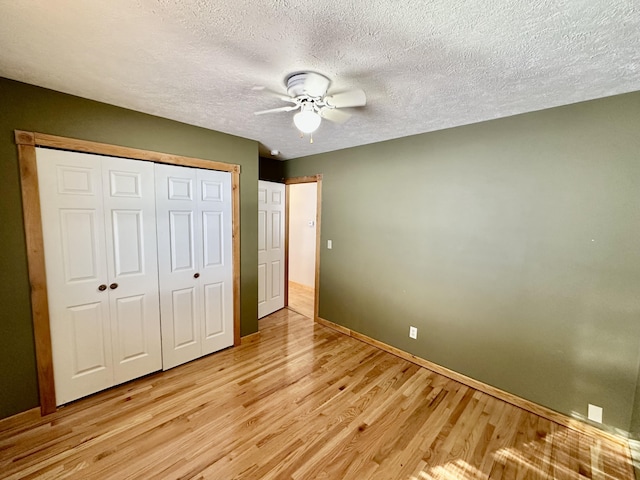 unfurnished bedroom featuring a textured ceiling, light hardwood / wood-style flooring, a closet, and ceiling fan