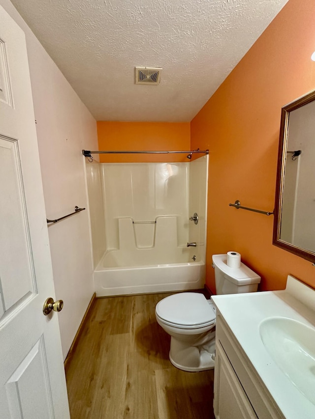 full bathroom featuring toilet, bathing tub / shower combination, a textured ceiling, vanity, and hardwood / wood-style flooring