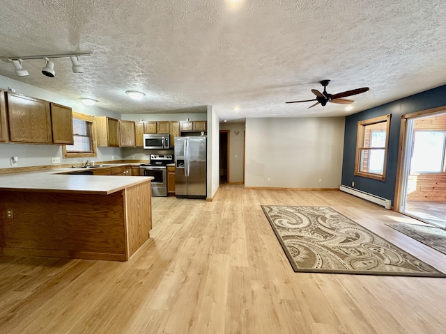 kitchen with sink, a baseboard radiator, appliances with stainless steel finishes, kitchen peninsula, and light hardwood / wood-style floors