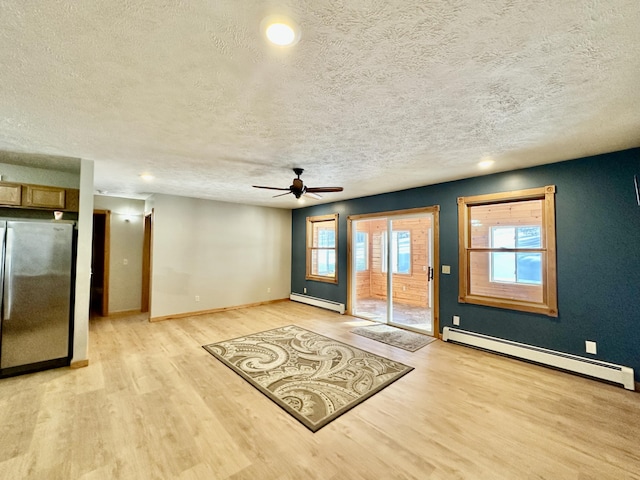 interior space featuring a baseboard heating unit, light hardwood / wood-style floors, and a textured ceiling