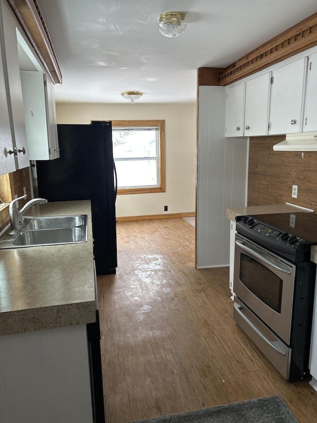 kitchen featuring stainless steel electric range oven, light hardwood / wood-style floors, sink, and white cabinets