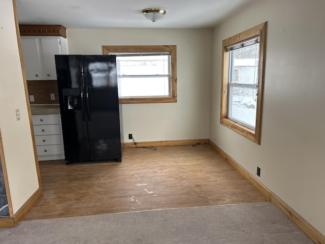 kitchen featuring black fridge with ice dispenser and light hardwood / wood-style flooring