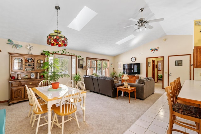 tiled dining space featuring ceiling fan and lofted ceiling with skylight