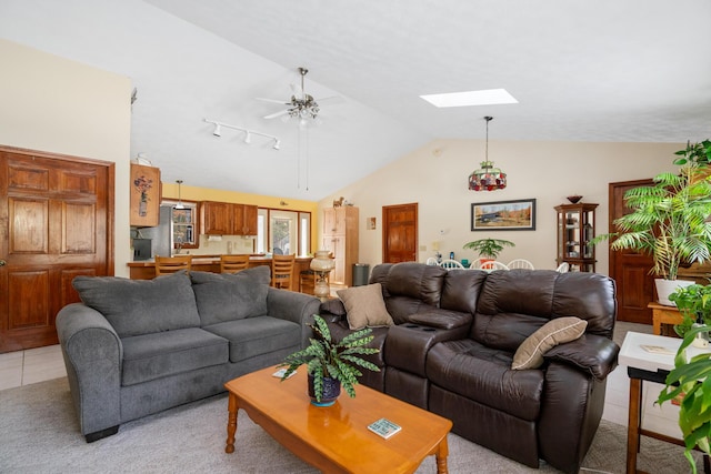 living room with light tile patterned floors, lofted ceiling with skylight, and ceiling fan