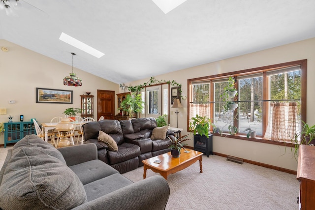 carpeted living room featuring vaulted ceiling with skylight