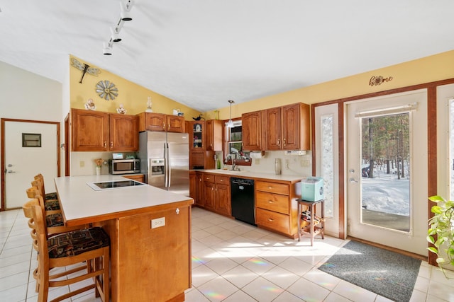 kitchen with lofted ceiling, sink, a breakfast bar, appliances with stainless steel finishes, and hanging light fixtures