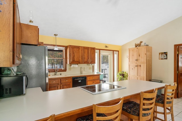 kitchen featuring pendant lighting, black appliances, sink, a kitchen breakfast bar, and kitchen peninsula